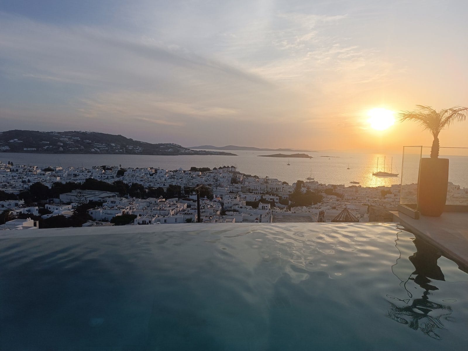 Sunset over Mykonos Town and the old port from an elevated pool terrace.